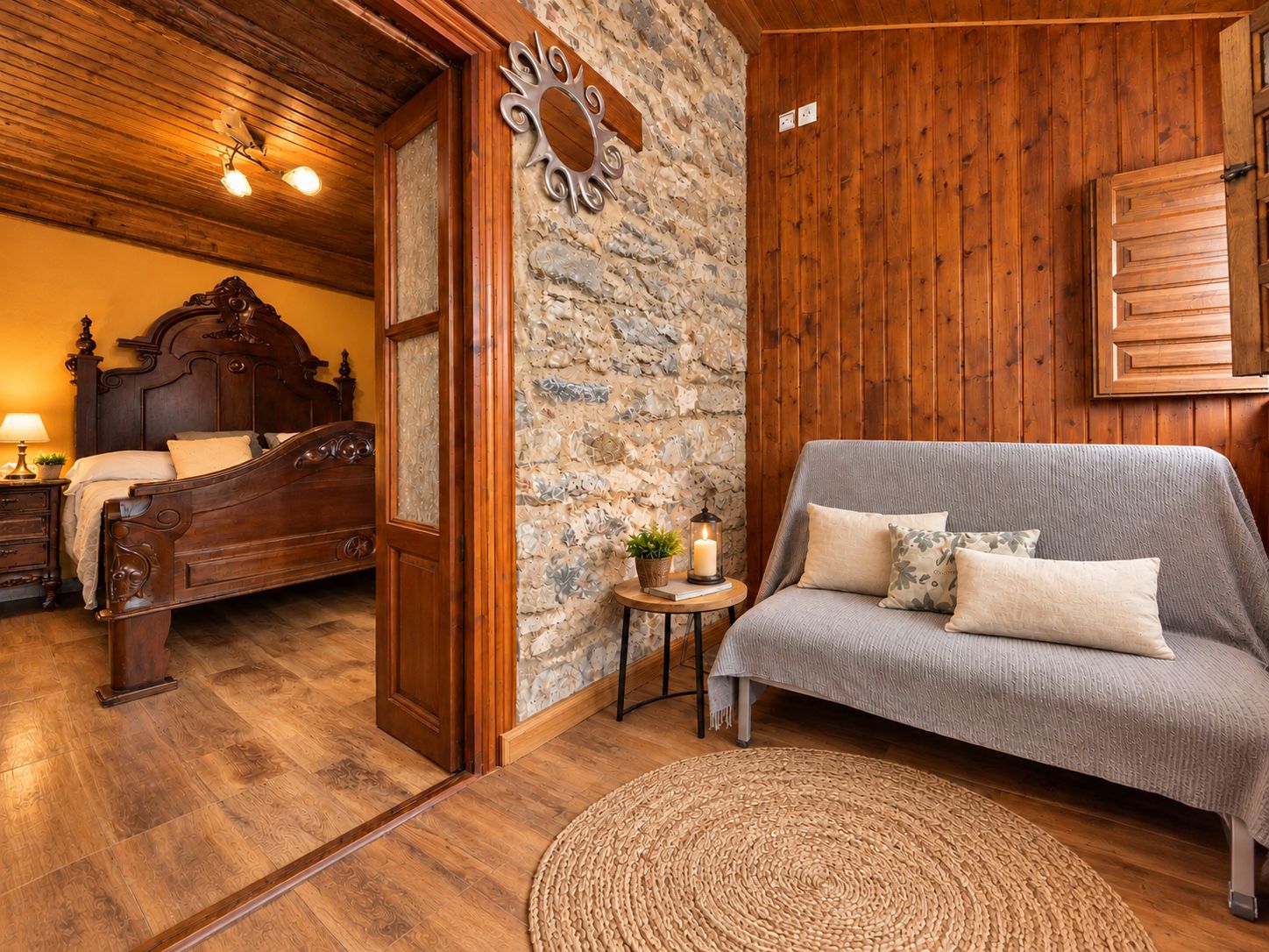 Une pièce au plancher de bois, avec un lit, un canapé et un mur en pierre.