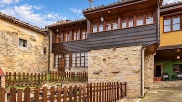Un bâtiment traditionnel en pierre, doté d’un balcon en bois et d’une clôture en bois.