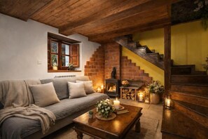 A cozy living room with a sofa, a fireplace, and a staircase. - La Congosta - Jacuzzi, fireplace, and mountains in Asturias (La Villa de Sub, teverga, asturias)