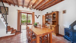 Una mesa de madera con sillas, una estantería, una hornilla y una escalera.
