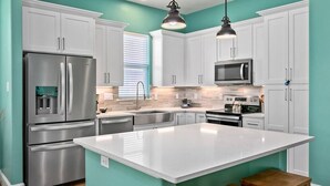 Una cocina moderna con armarios blancos, electrodomésticos de acero inoxidable y una isla grande.