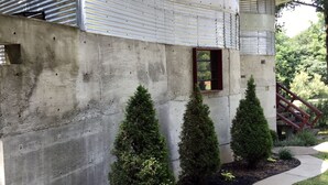A modern house with a concrete facade, a metal roof, and a small window. - One of a kind cabin in the woods.  Quiet and private but close to everything.  (Coxs Creek)