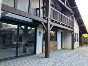 Un bâtiment à deux étages doté d’un balcon, de grandes fenêtres et d’une terrasse en bois.