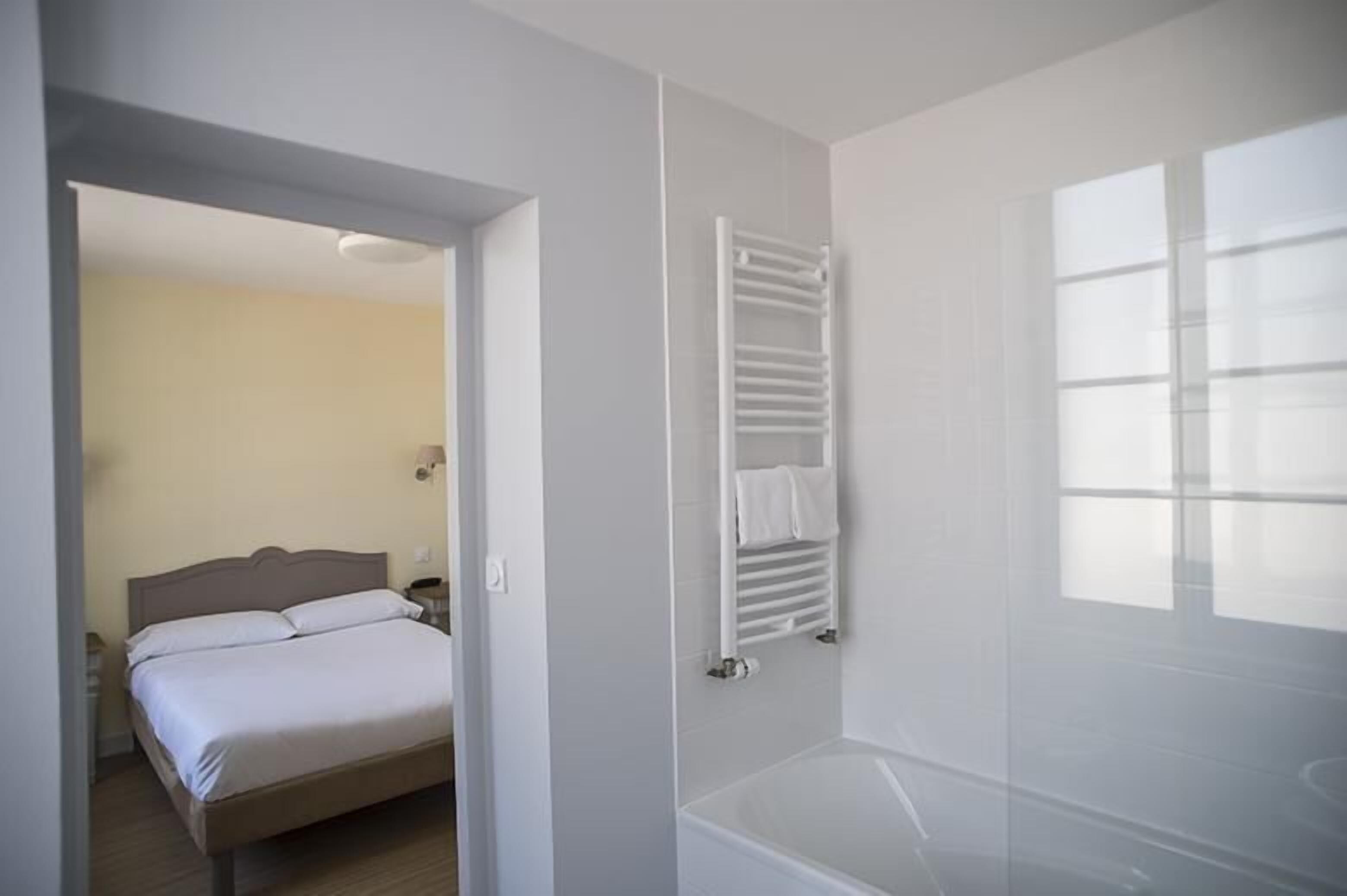 A hotel room with a bed, a white radiator, and a window.