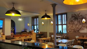 Un restaurante con muebles de madera, iluminación colgante y un mural en la pared.