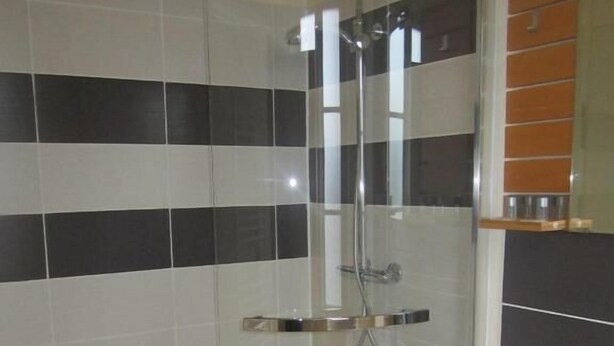 Un baño con ducha, lavabo y espejo.