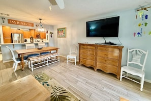 A modern kitchen with wooden cabinets, a dining table, and a TV mounted on the wall. - Updated 2 bedroom/2.5 bath townhouse, perfect for a large family beach getaway!! (Saint Augustine)