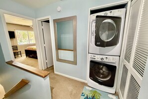 A laundry room with a washer and dryer, a mirror, and a window with a view of the outdoors. - Updated 2 bedroom/2.5 bath townhouse, perfect for a large family beach getaway!! (Saint Augustine)
