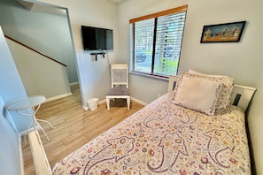 A bedroom with a bed, a chair, a television, and a window with blinds. - Updated 2 bedroom/2.5 bath townhouse, perfect for a large family beach getaway!! (Saint Augustine)