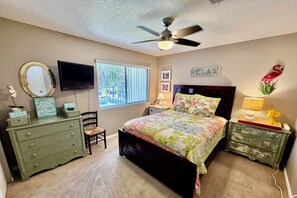 A bedroom with a bed, dresser, vanity, television, ceiling fan, window, and wall decorations. - Updated 2 bedroom/2.5 bath townhouse, perfect for a large family beach getaway!! (Saint Augustine)