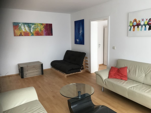 A living room with a sofa, a black chair, a glass coffee table, and a wooden crate. - HOLIDAY in Neckarsteinach (Neckarsteinach)