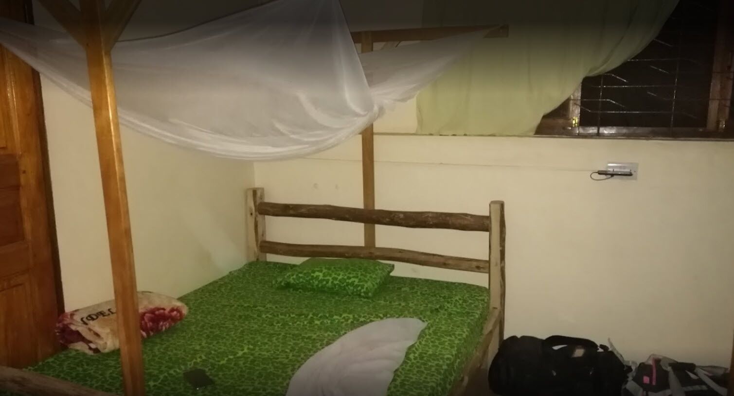 A single bed with a wooden frame and green patterned bedding.