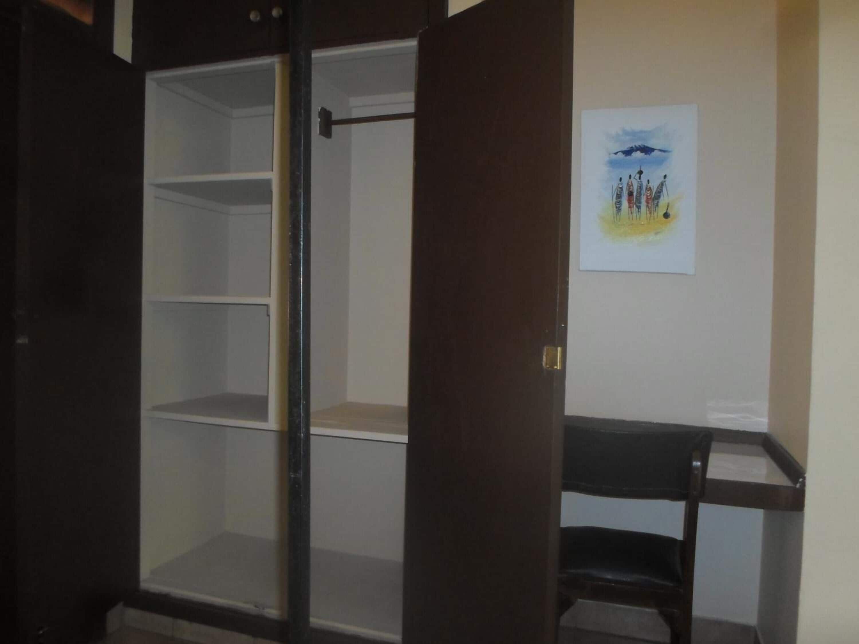 Une pièce comprenant une grande armoire, une chaise et un tableau accroché au mur.