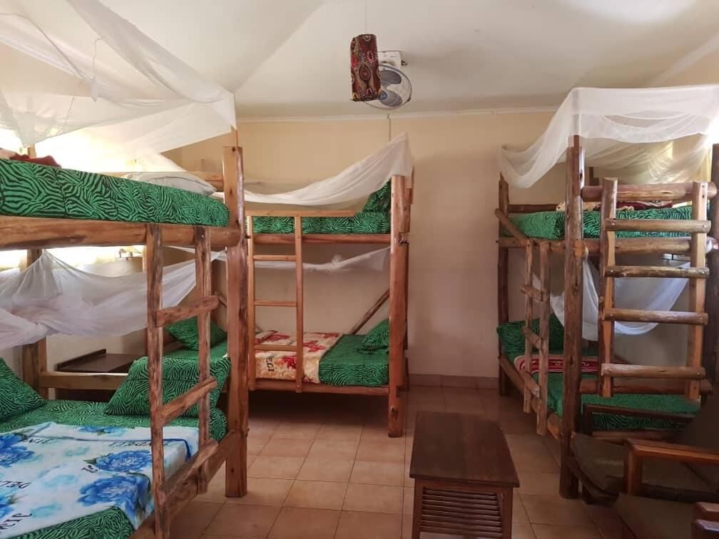 A room with bunk beds, a fan, and a small table.