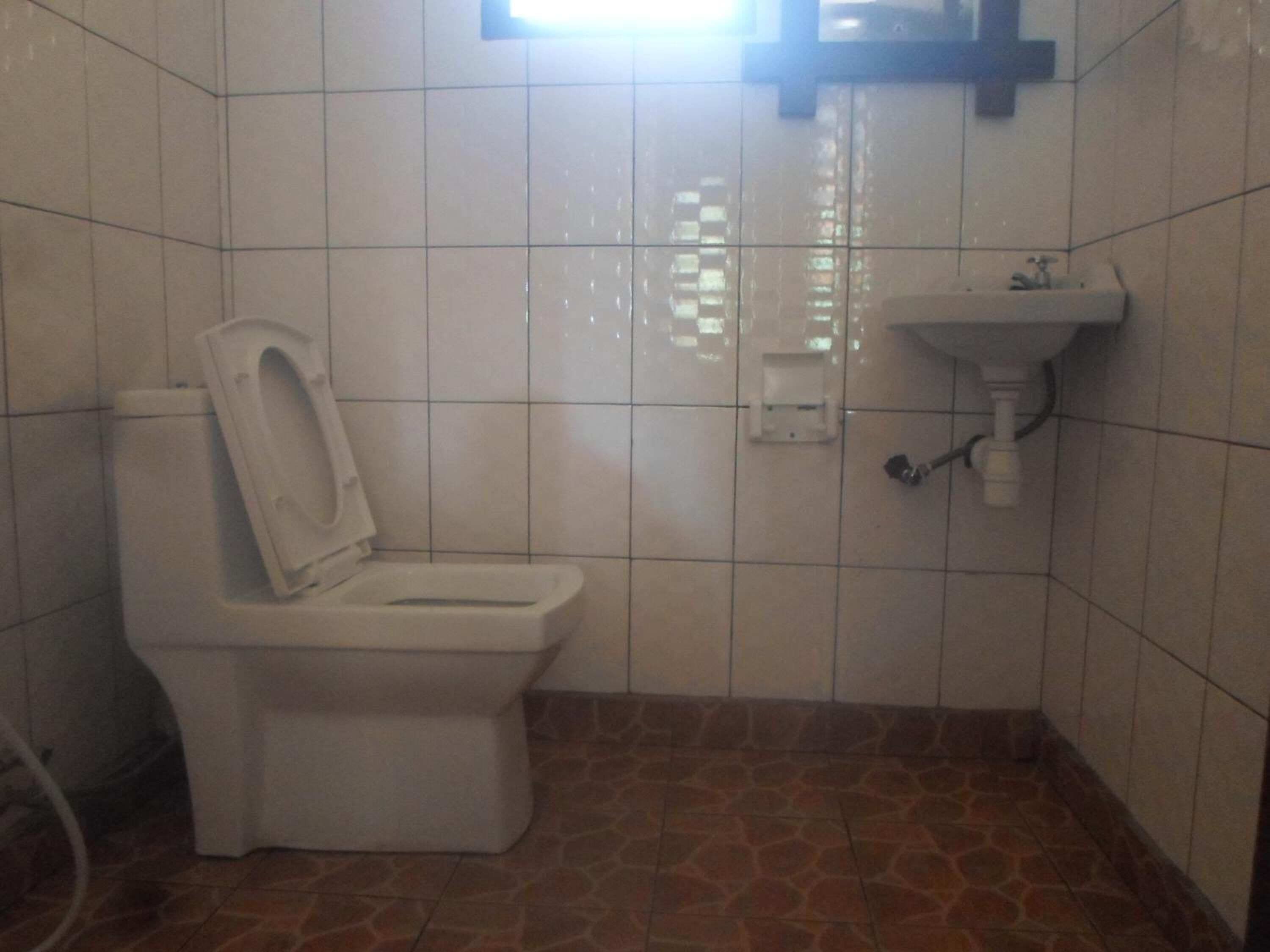 A small bathroom with a toilet, a sink, and tiled walls.