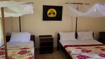 A room with two beds, each with a canopy. There is a nightstand between the beds, and a framed picture on the wall.
