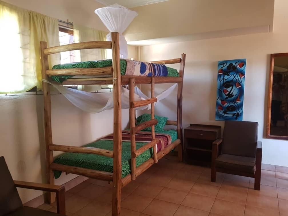 A bunk bed room with a desk and chair, a painting on the wall, and a window with curtains.
