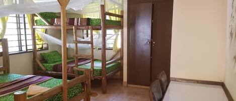 A room with bunk beds, a dining table, and a door.