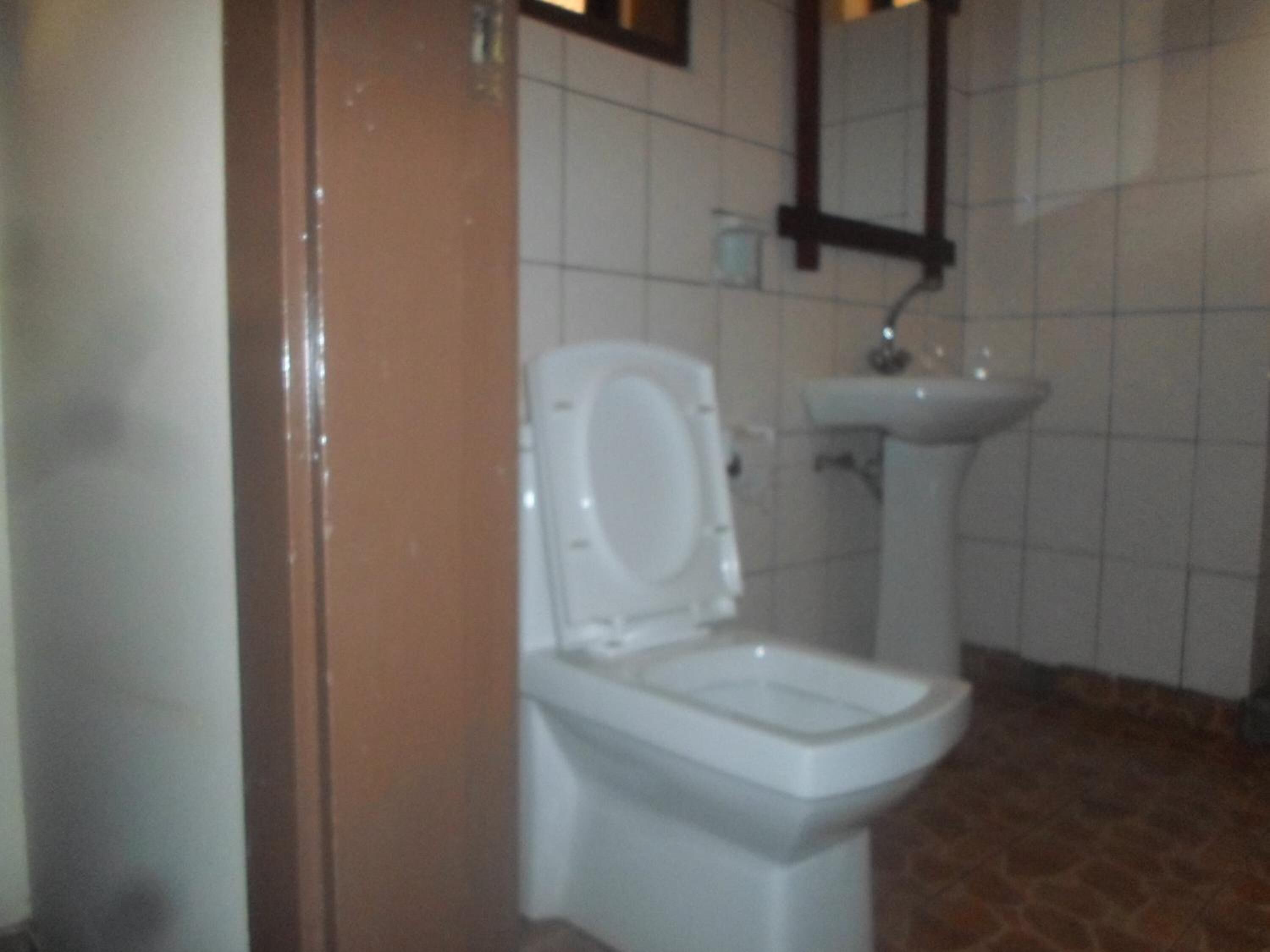 A bathroom with a toilet, sink, and tiled walls.