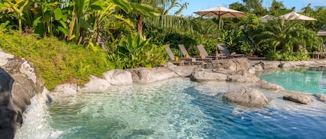 Alberca al aire libre, sombrillas en la alberca y camastros