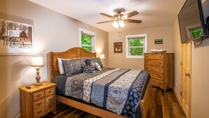 A bedroom with a wooden bed, a nightstand with drawers, a ceiling fan, and a dresser. - Cozy Cottage - Located on App Ski Mtn Lower level game room, Firepit (Blowing Rock)