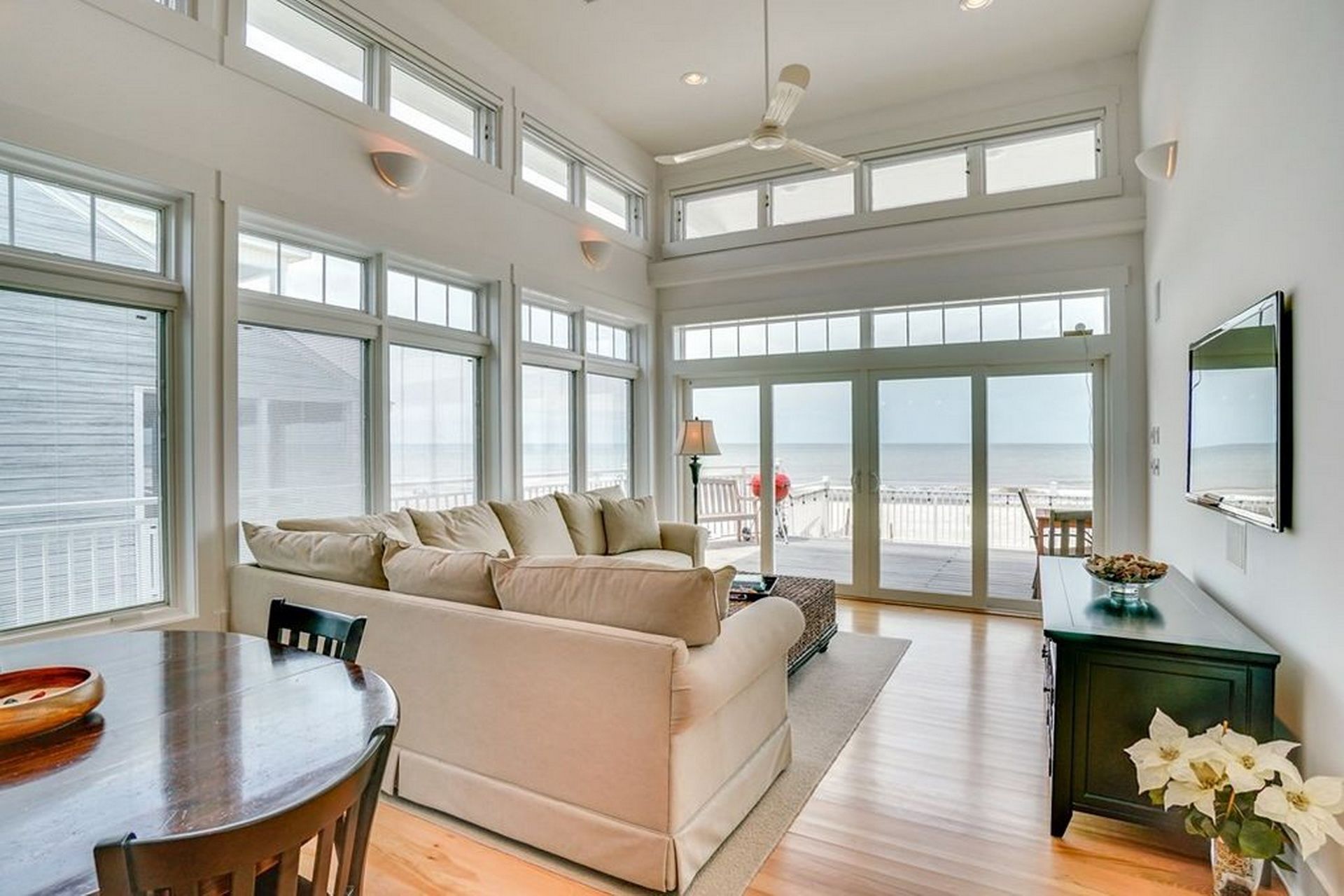 A spacious living room with a large window overlooking the ocean, a cozy seating area, and a dining table.
