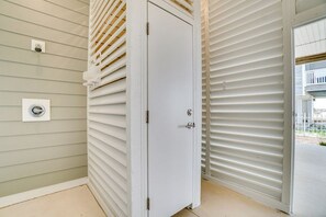 Eine weiße Tür mit Griff, ein Fenster mit Rollläden und ein Lichtschalter an der Wand.