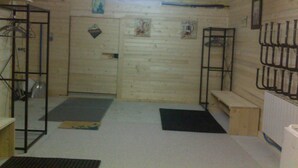 A room with a wooden door, a bench, a black mat, a metal rack, and a white sink. - SLOPESIDE CHALET (DOUCY VALMOREL)