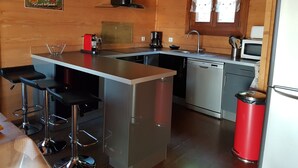 A compact kitchen with a central island, bar stools, a coffee maker, and a microwave. - SLOPESIDE CHALET (DOUCY VALMOREL)