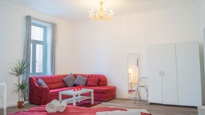 Ein modernes Wohnzimmer mit einem roten Sofa, einem weißen Couchtisch und einer Kronleuchter.