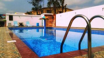 Relax by the pool surrounded by a geometric patterned floor and lounge chairs with striped cushions.