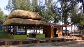 A thatched-roof structure with a mural, a fenced area, and a paved walkway. - Mohana  Beach Resort (Kanthi)