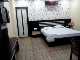 A bedroom with a bed, a TV, a wardrobe, and an air conditioner.