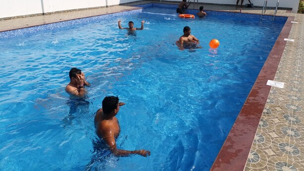 A swimming pool with clear blue water, a tiled edge, and a white wall. - Mohana  Beach Resort (Kanthi)