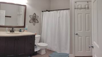 Een bad/douchecombinatie, een haardroger, handdoeken, zeep