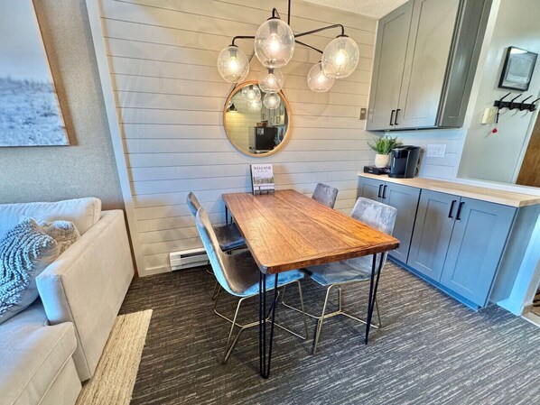 Een moderne keuken met een houten tafel, blauwe stoelen en een bijzondere lamp.
