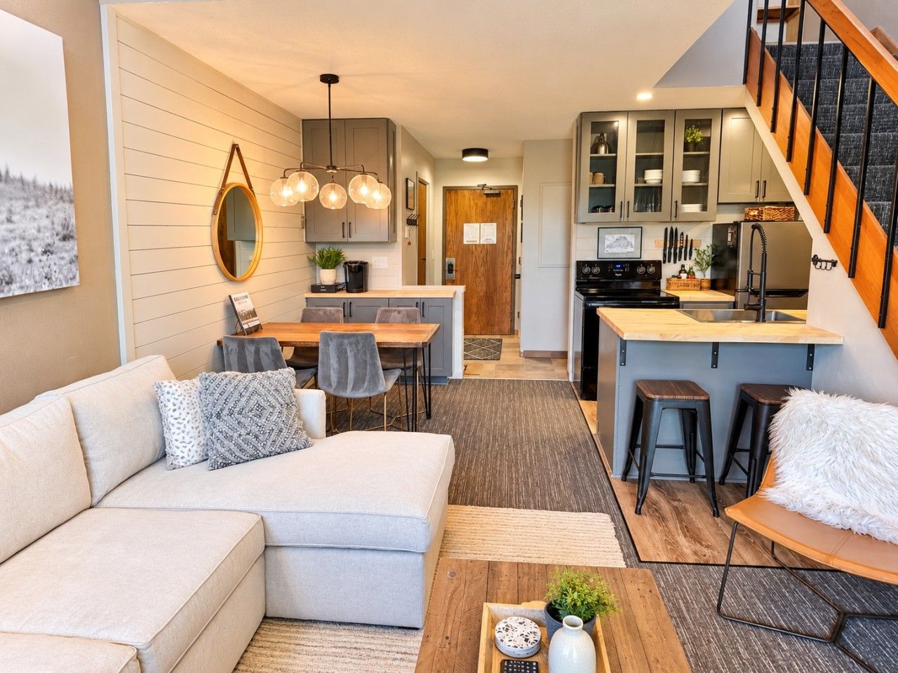 A modern living room with a sectional sofa, a dining area, and a kitchen with a central island.