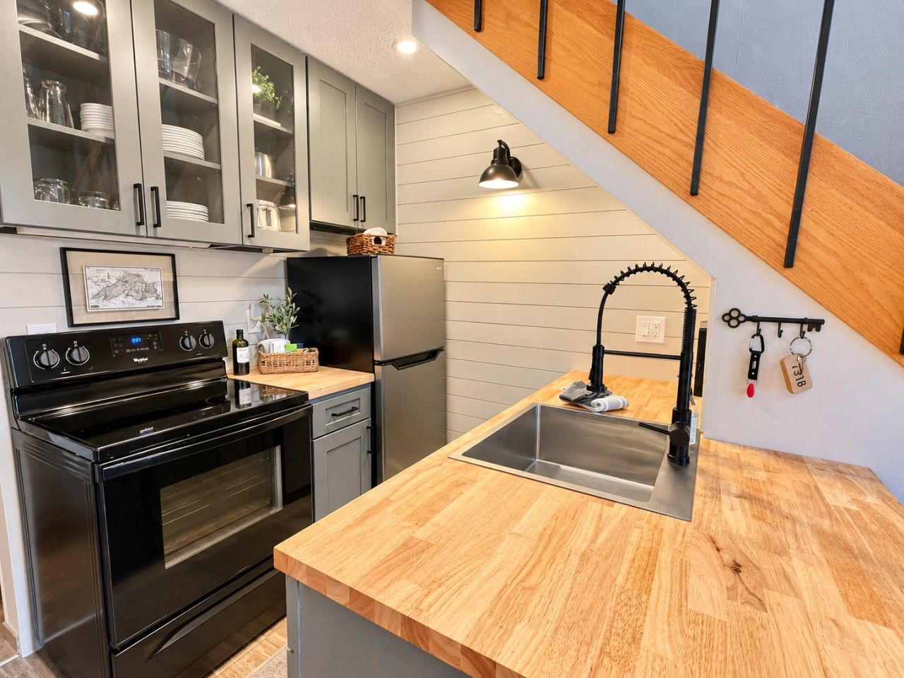 Une cuisine dotée d’un plan de travail en bois, d’un évier en acier inoxydable et d’une cuisinière noire.