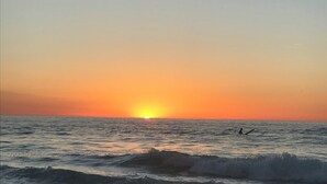 A sunset over the ocean with waves and a person in the water. - Le domaine de frehel (Frehel)