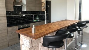 A modern kitchen with a wooden bar counter and black bar stools. - Le domaine de frehel (Frehel)
