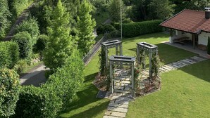 En trädgård med en lusthus, en gångstig och en byggnad med ett rött tak.