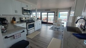 Una cocina moderna con electrodomésticos de acero inoxidable, un ventanal y vista al mar.