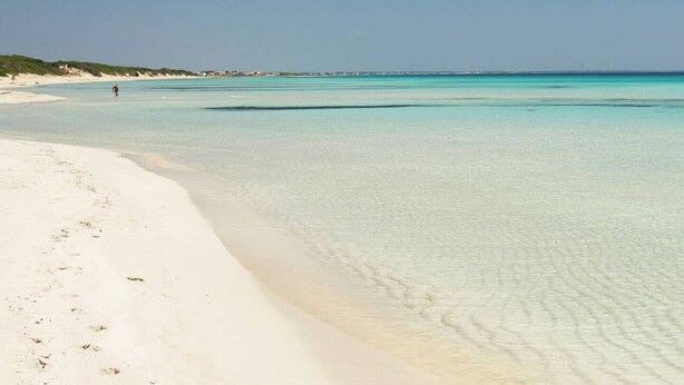 Une plage à l’eau turquoise et au sable blanc.