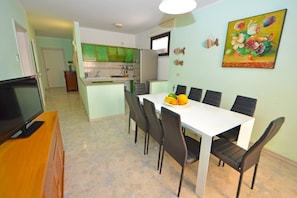 Cozy living space with a dining area, flat-screen TV, and kitchen in the background.