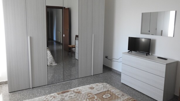 Une chambre avec une armoire, un téléviseur et un miroir.