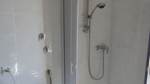 Une salle de bain équipée d’un lave-linge, d’une douche et de toilettes.