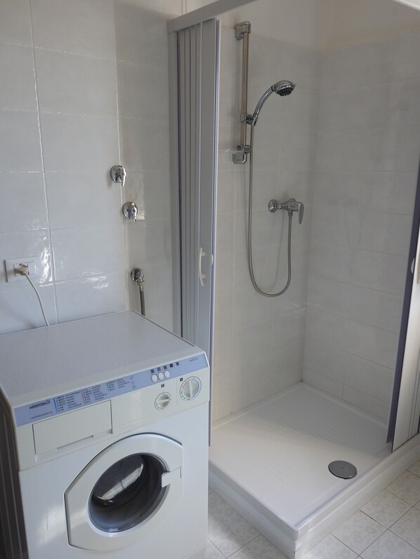 Ein Badezimmer mit Waschmaschine, Dusche und Toilette.
