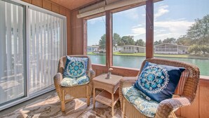 A covered outdoor seating area with wicker furniture and a view of a lake and houses. - Beach House with a lake.  (Surfside Beach)