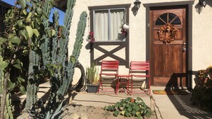 A building with a wooden door, a window with curtains, and a cactus plant. - Charming Hidden Cottage (Los Gatos)