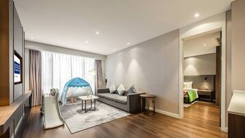 A modern living room with a sofa, a small table, a play tent, and a wooden floor.
